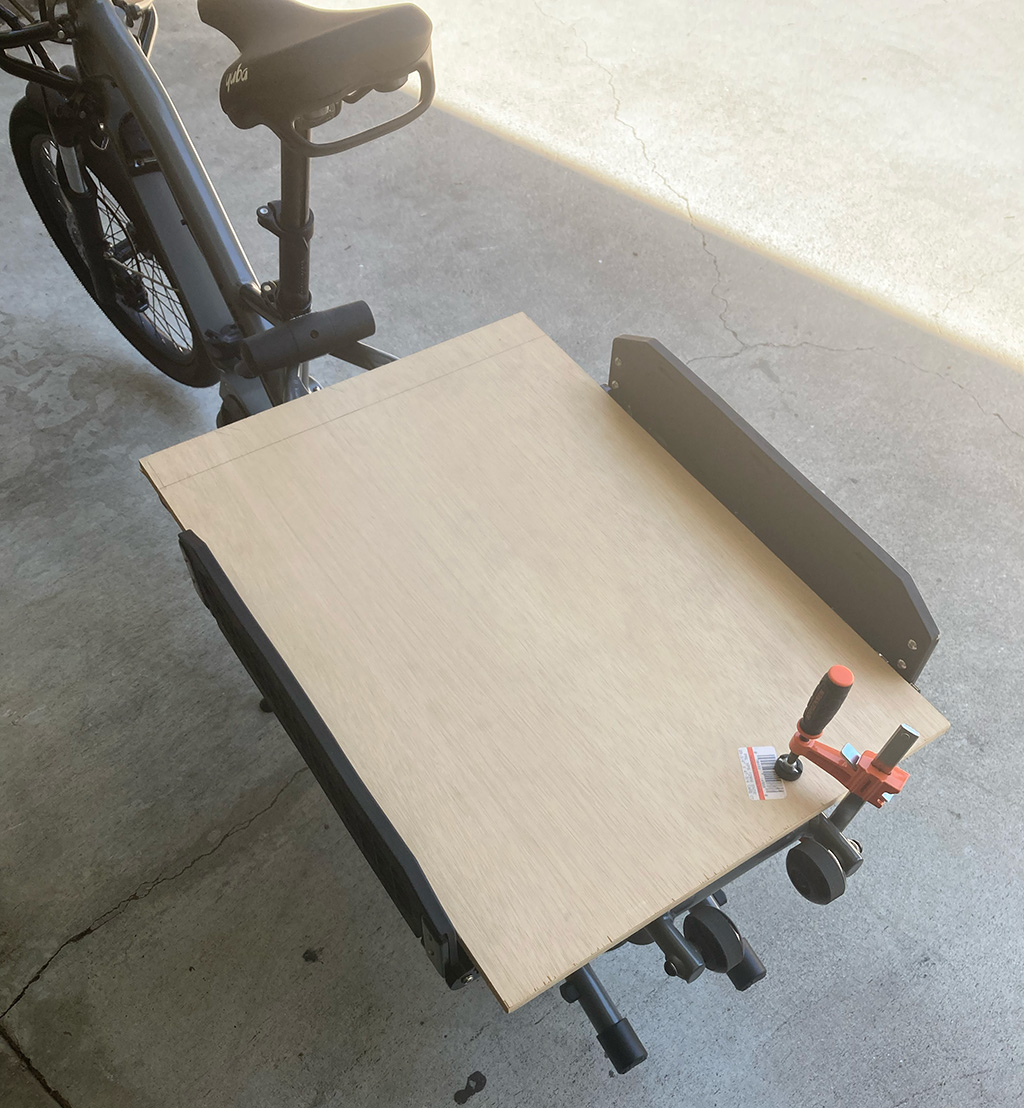Photo of a sheet of plywood clamped to the bed of the bike