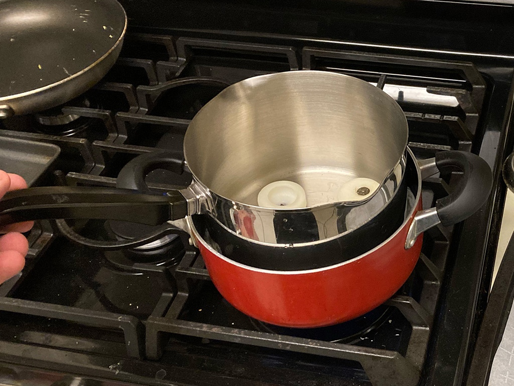 Photo of double boiler on stove; the inner pot already has candle wax melting in it