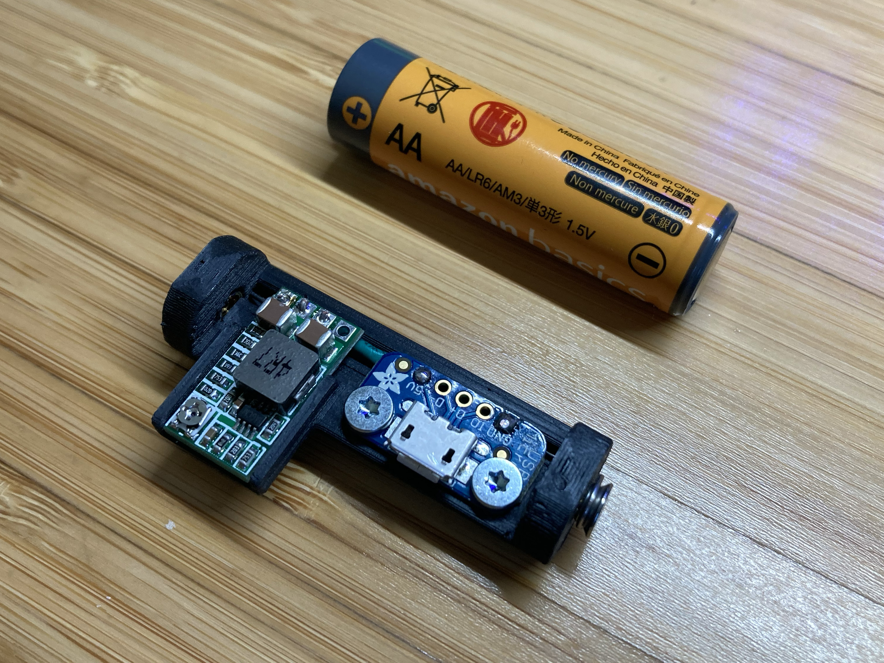 Photo of assembled shim next to a real AA battery for comparison
